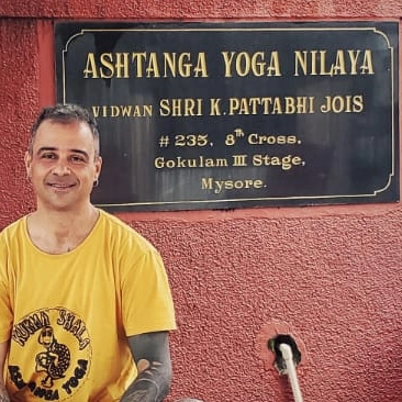 Marcelo Holanda em frente à placa do Ashtanga Yoga Nilaya, em Mysore, Índia